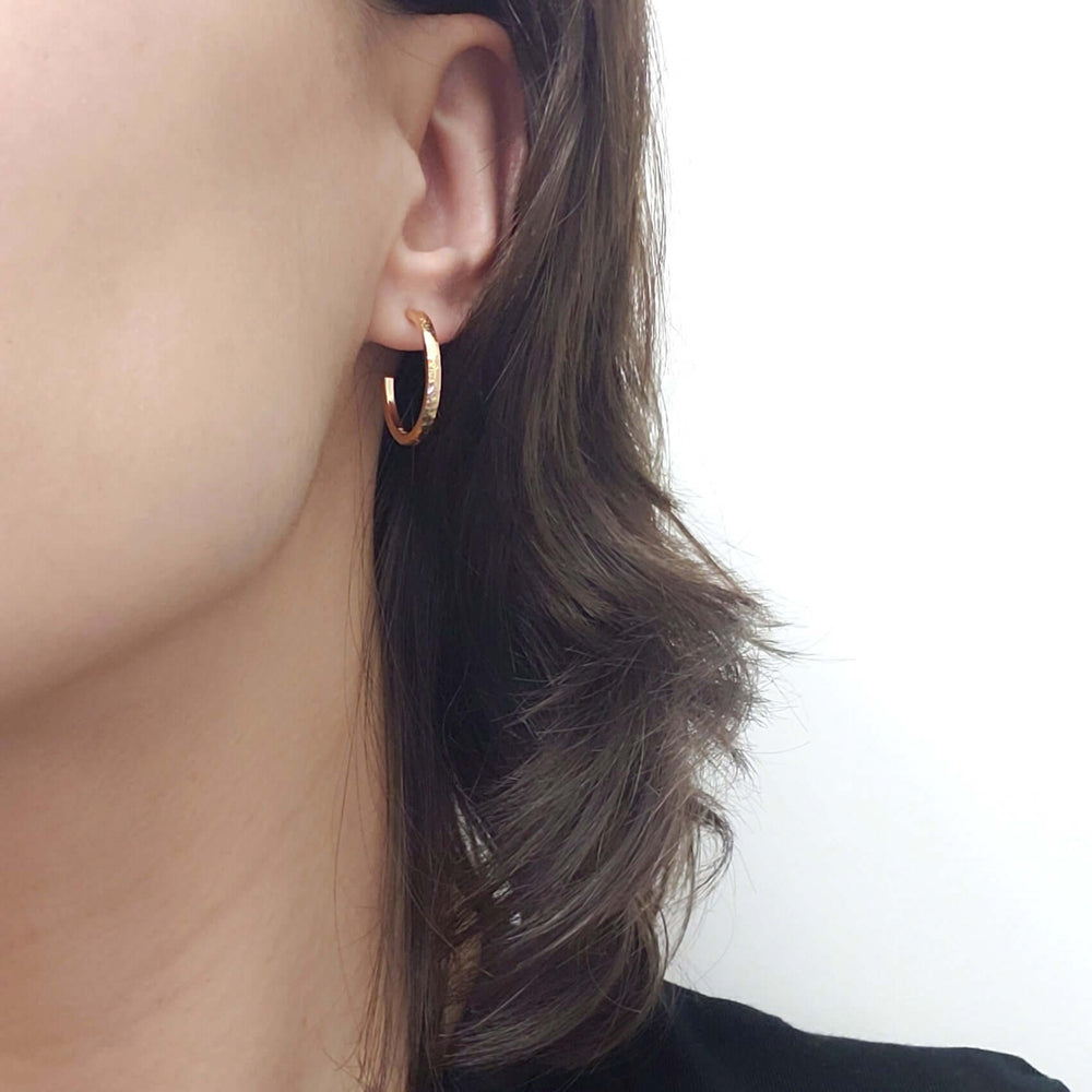 14kt yellow gold textured hoop earring worn on an ear