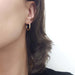 14kt yellow gold textured hoop earring worn on an ear