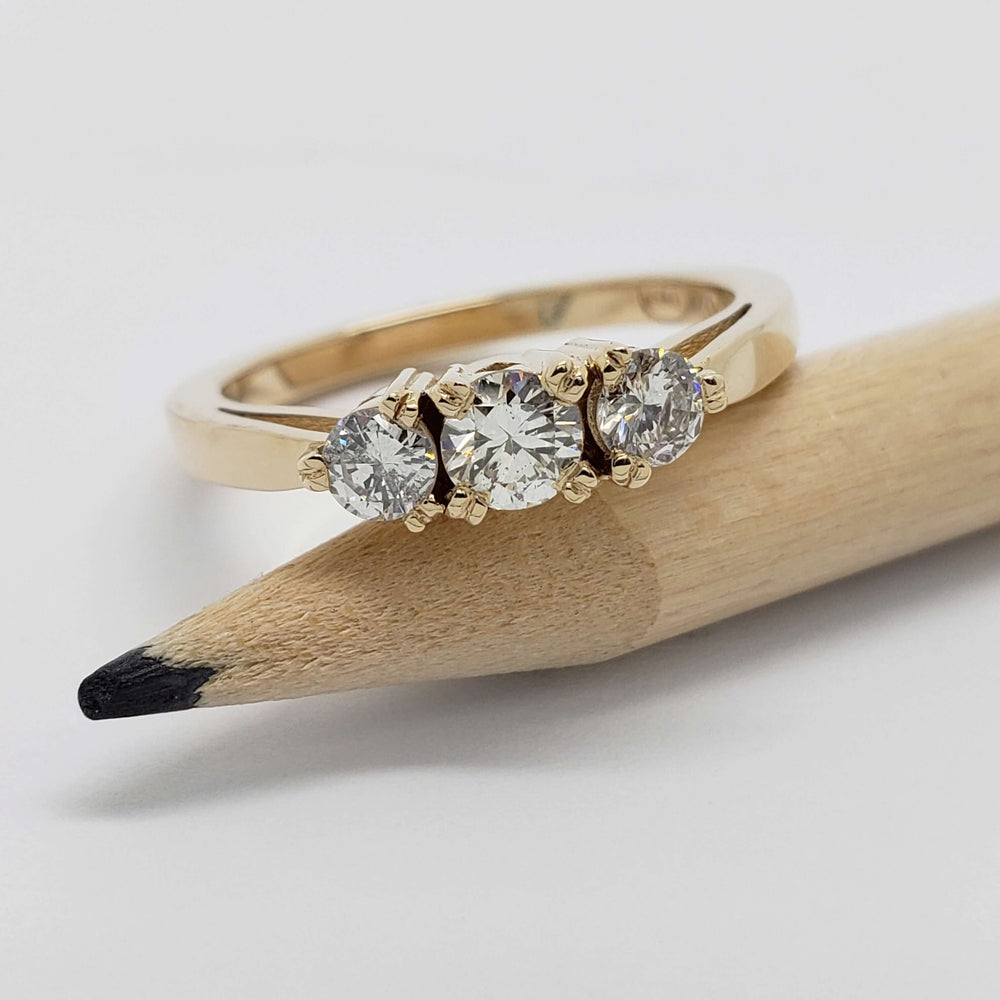 14kt yellow gold three-stone diamond ring displayed on a pencil