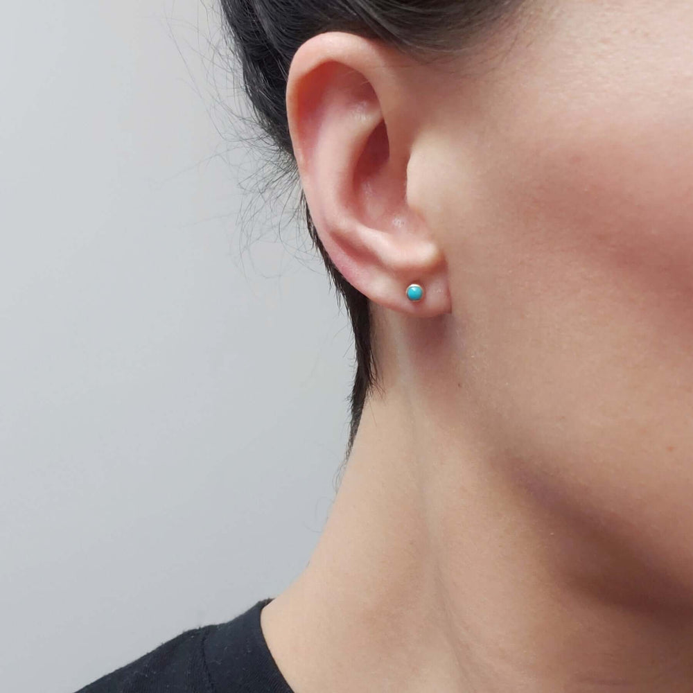 Turquoise cabochon stud earring in 14kt yellow gold worn on ear