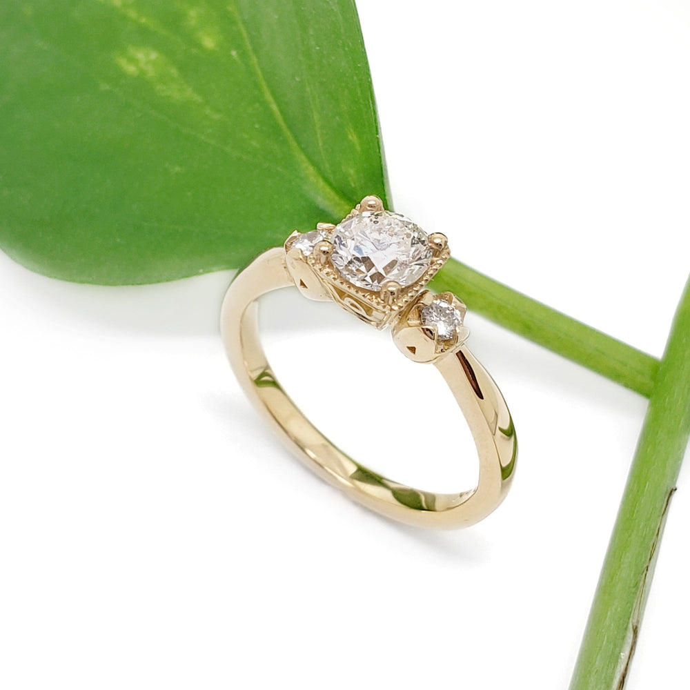 14kt yellow gold vintage diamond engagement ring beside a green leaf, angled view