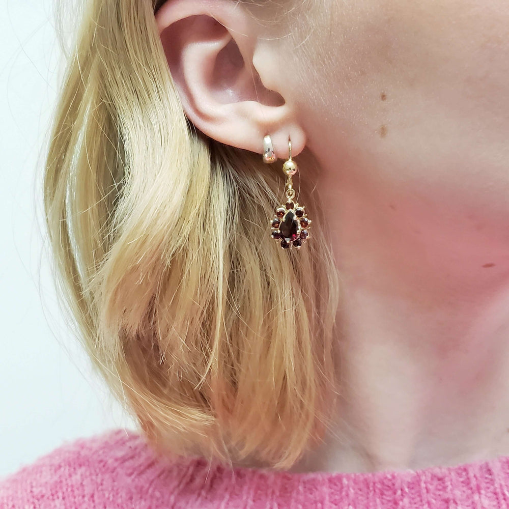 Vintage-inspired 14kt yellow gold garnet dangle earring worn on ear