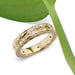 14kt yellow gold wedding band with engraved floral pattern and Canadian diamonds, near green leaf