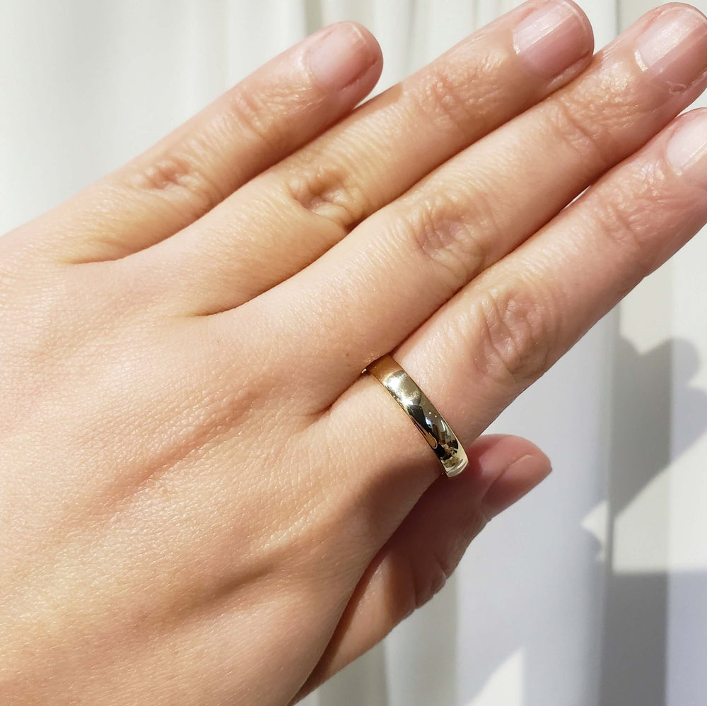 14kt yellow gold wedding ring worn on hand, showing low dome profile