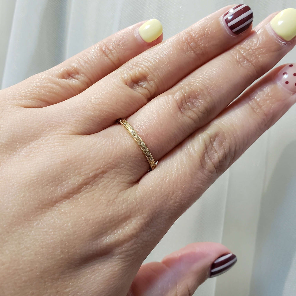 14kt yellow gold wheat engraved wedding ring shown worn on a hand