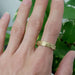 14kt yellow gold woodgrain wedding ring shown on a hand