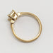 A yellow gold ring with a bezel-set round diamond, shown from a top-down perspective on a light gray background.