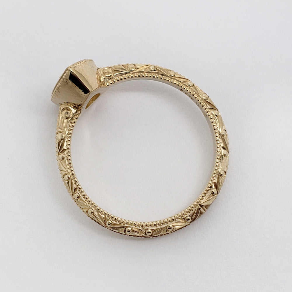 A yellow gold ring blank with an ornate, engraved filigree band and a flat, unset crown, photographed on a clean white background.