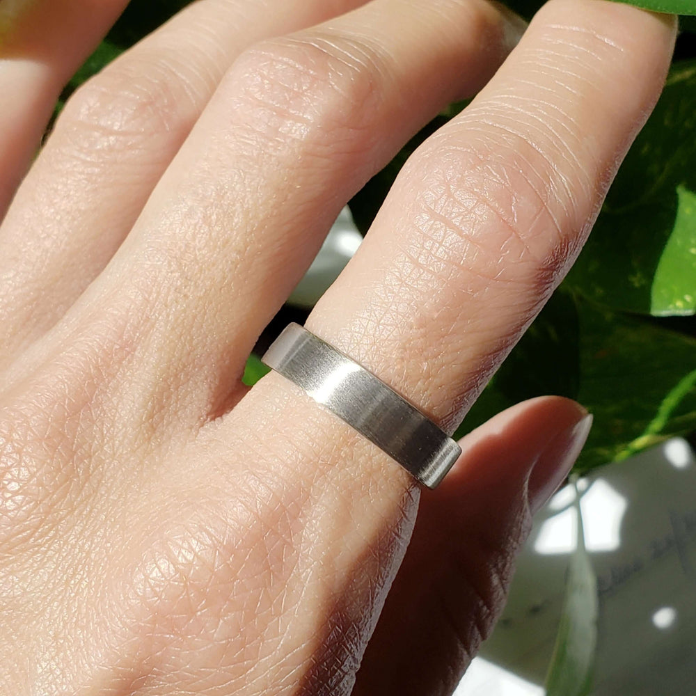 5mm brushed 14kt white gold wedding ring worn on hand in natural light