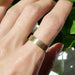 5mm brushed 14kt yellow gold wedding ring shown on hand in natural light