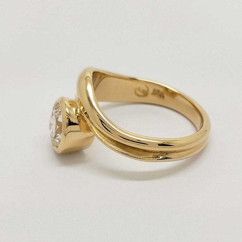 Angled side view of 14kt yellow gold curvy engagement ring with bezel-set lab diamond