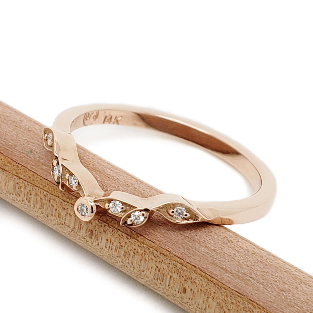Angled view of 14k rose gold leaf wedding ring with Canadian diamonds on wood