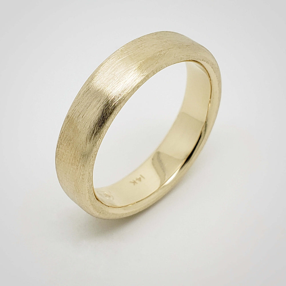 Angled view of 14k yellow gold brushed wedding band on white background