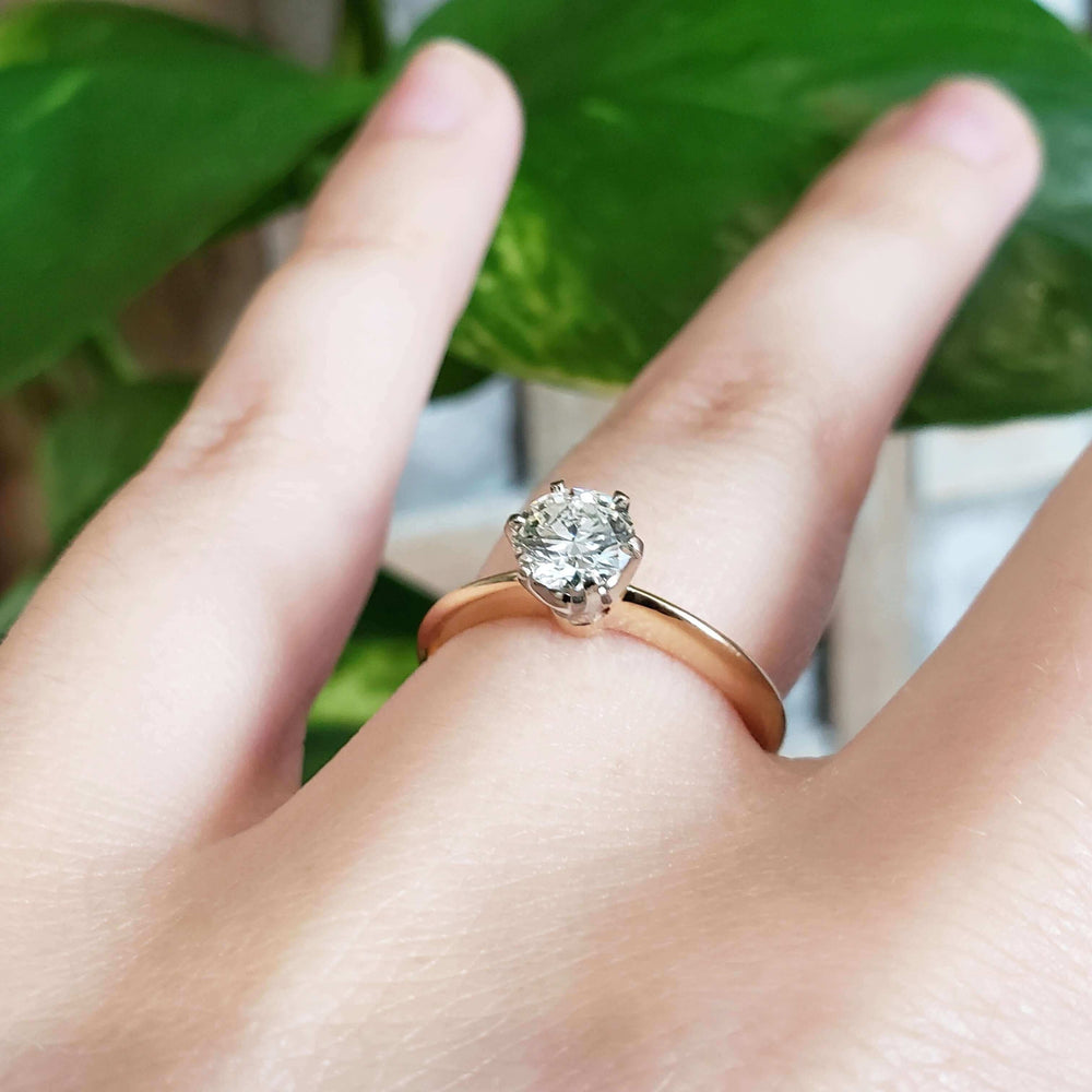 Angled view of diamond solitaire ring in yellow and white gold on hand