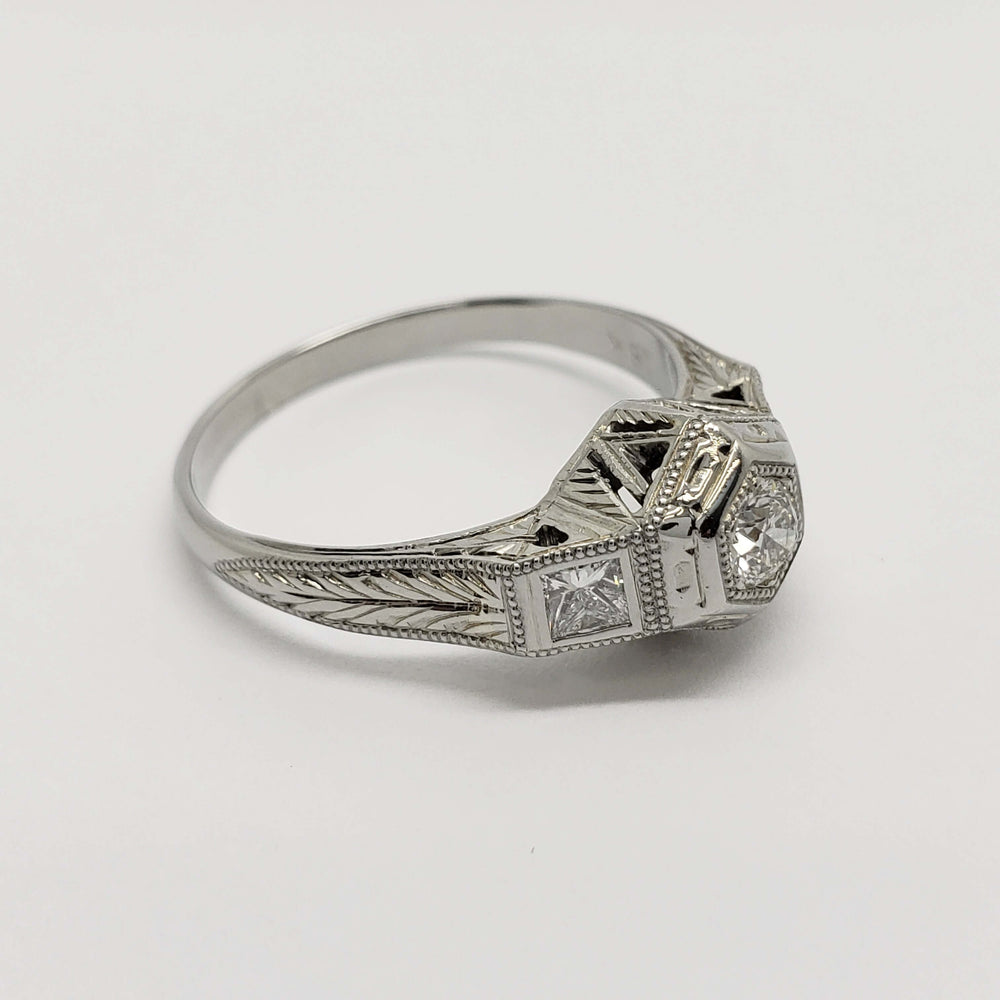 Angled view of engraved 18kt white gold diamond ring with hexagon and millgrain details