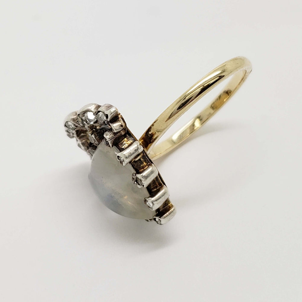 Angled view of moonstone heart ring with diamond accents and yellow gold band