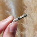 Hand holding antique 10kt white gold pin with pearls and square blue sapphire