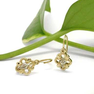 Antique 14kt yellow gold quatrefoil earrings with lab-grown diamonds, shown with a green leaf