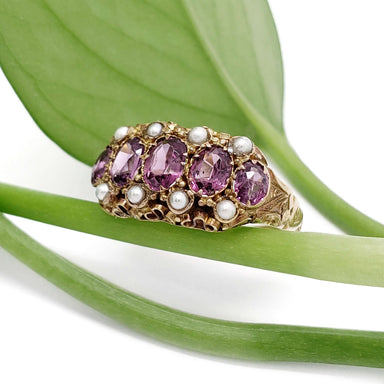 Antique 15kt yellow gold ring with purple fluorite and pearls, displayed on a green leaf