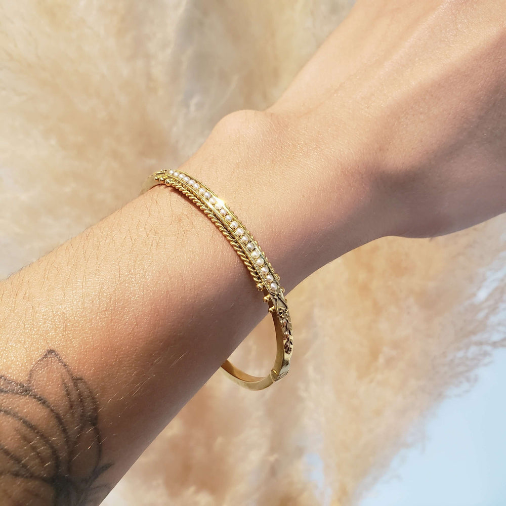 Antique 15kt yellow gold and seed pearl bangle worn on wrist