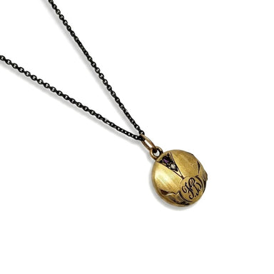Antique gold-toned round locket necklace with engraved F.B. monogram and two stones on black chain