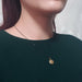 Antique gold-toned round locket on a model in a dark green top