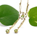 Antique peridot and pearl negligee necklace in 14kt gold displayed with green leaves