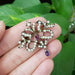 Antique silver brooch with pearls and amethysts shown in hand for scale
