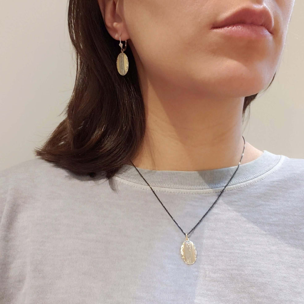 Model wearing antique yellow and white gold oval earrings and matching pendant necklace