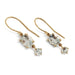 14kt yellow gold aquamarine dangle earrings displayed on a stand with green leaves