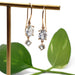 14kt yellow gold aquamarine dangle earrings displayed on a stand with green leaves