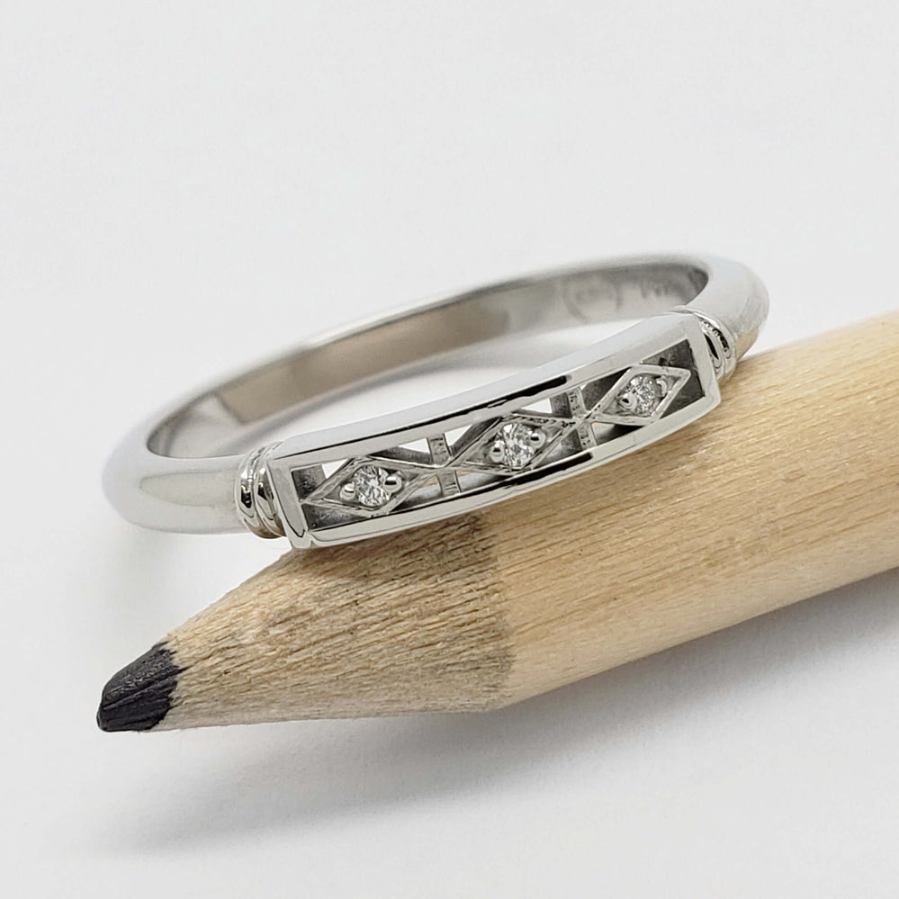 Art Deco style 14kt white gold ring with three Canadian diamonds, shown on a pencil
