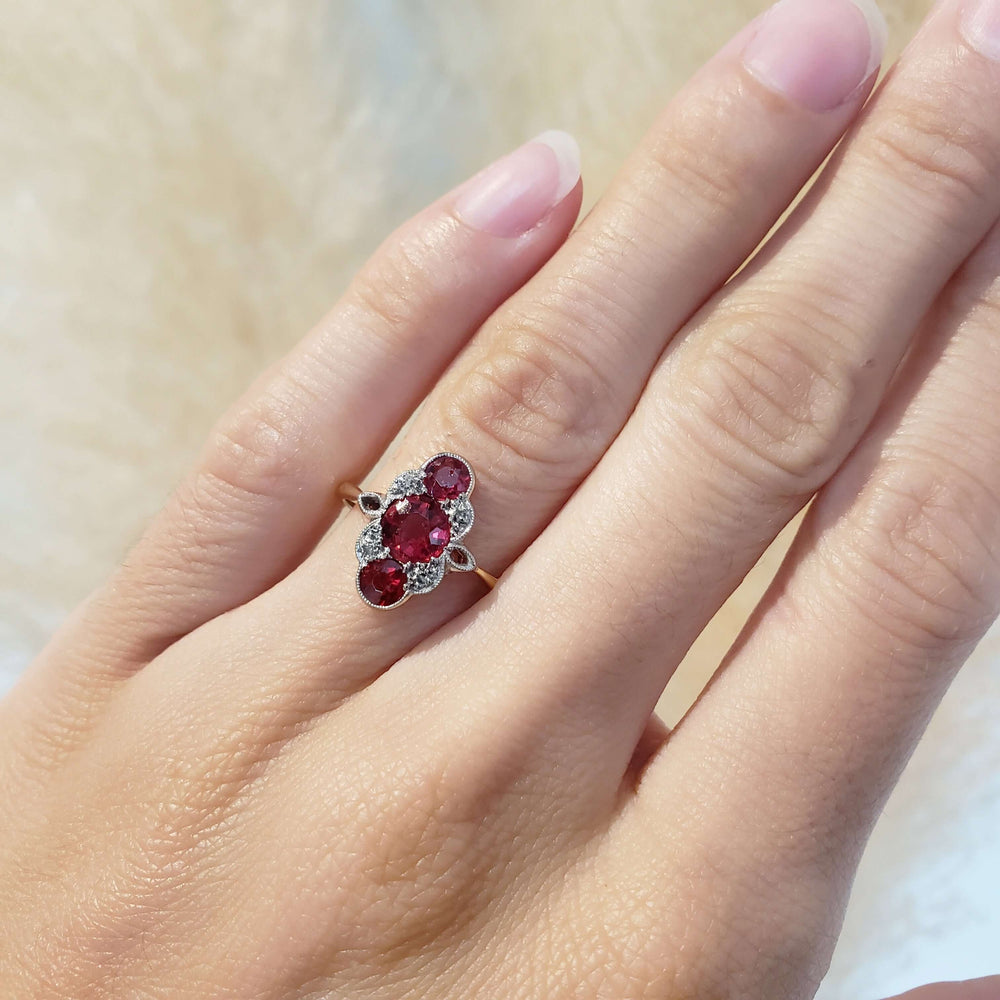 Art Deco 18kt gold ring with red glass and diamonds shown on a hand