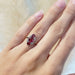 Art Deco 18kt gold ring with red glass and diamonds shown on a hand