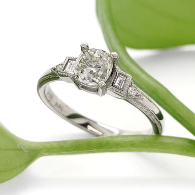 Art Deco inspired white gold ring with antique diamond, shown with green leaf