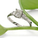 Art Deco inspired white gold ring with antique diamond, shown with green leaf