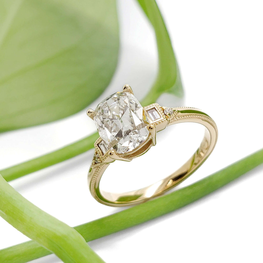 Art Deco inspired yellow gold engagement ring with lab diamond, shown with green leaf