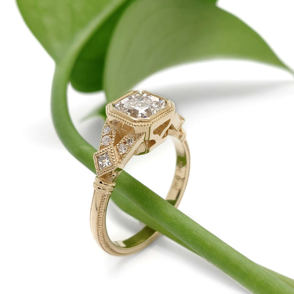 Art Deco style 14kt yellow gold ring with asscher cut lab diamond shown on a green leaf