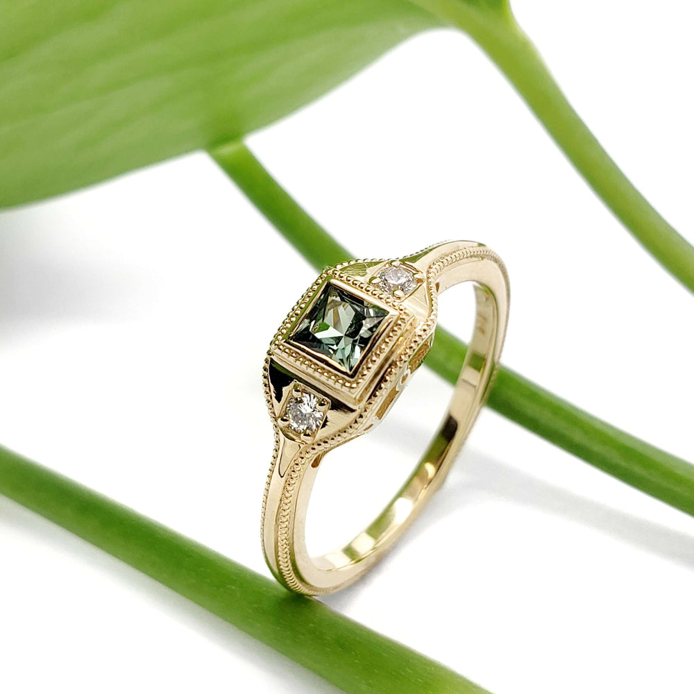 Art Deco inspired 14kt yellow gold ring with green lab sapphire and diamonds, on leaf background