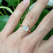 Asscher cut lab diamond yellow gold ring shown on hand with green background
