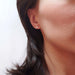 Asscher cut lab diamond stud earring in 14kt yellow gold shown on ear