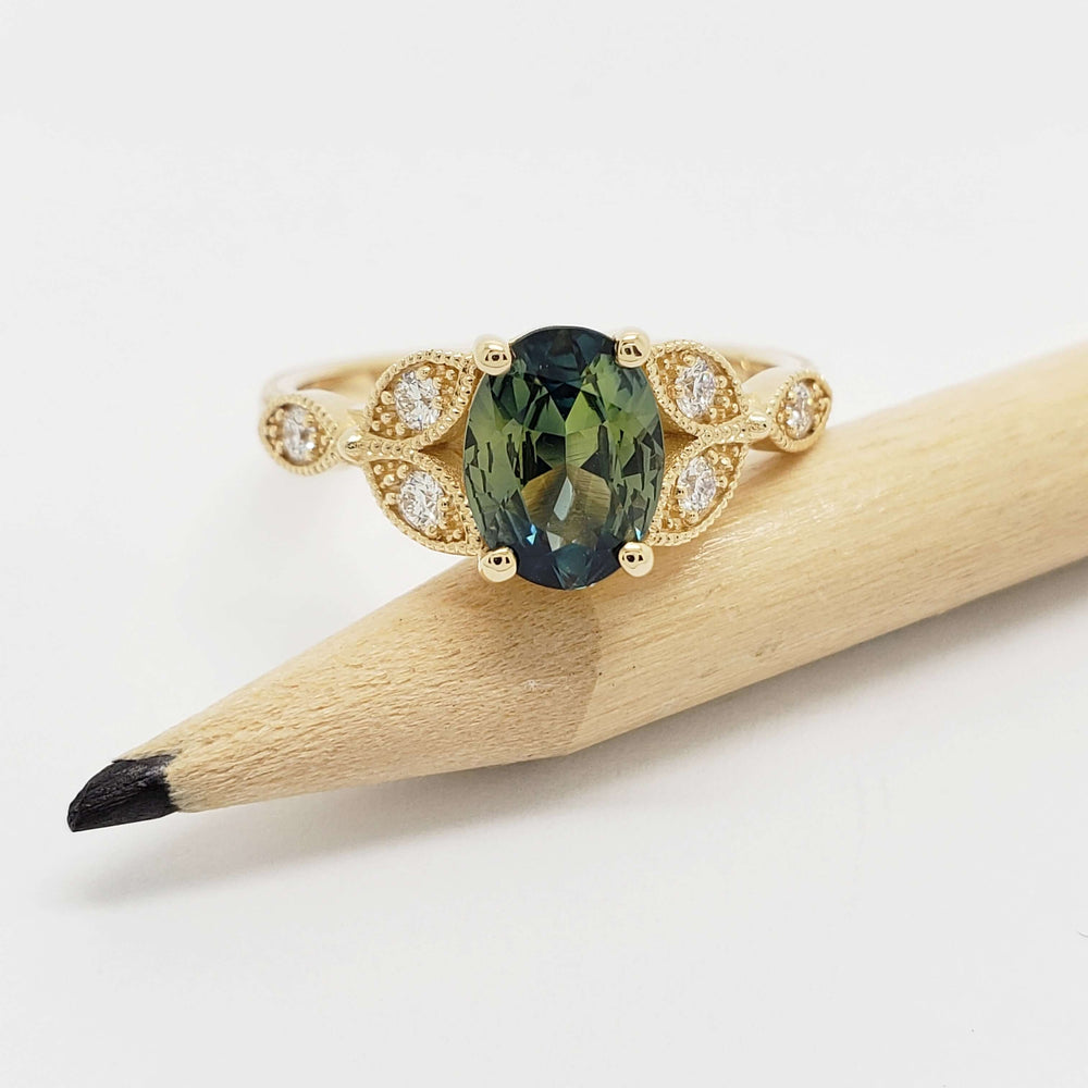 Oval Australian sapphire and diamond 14kt yellow gold ring shown beside pencil for scale