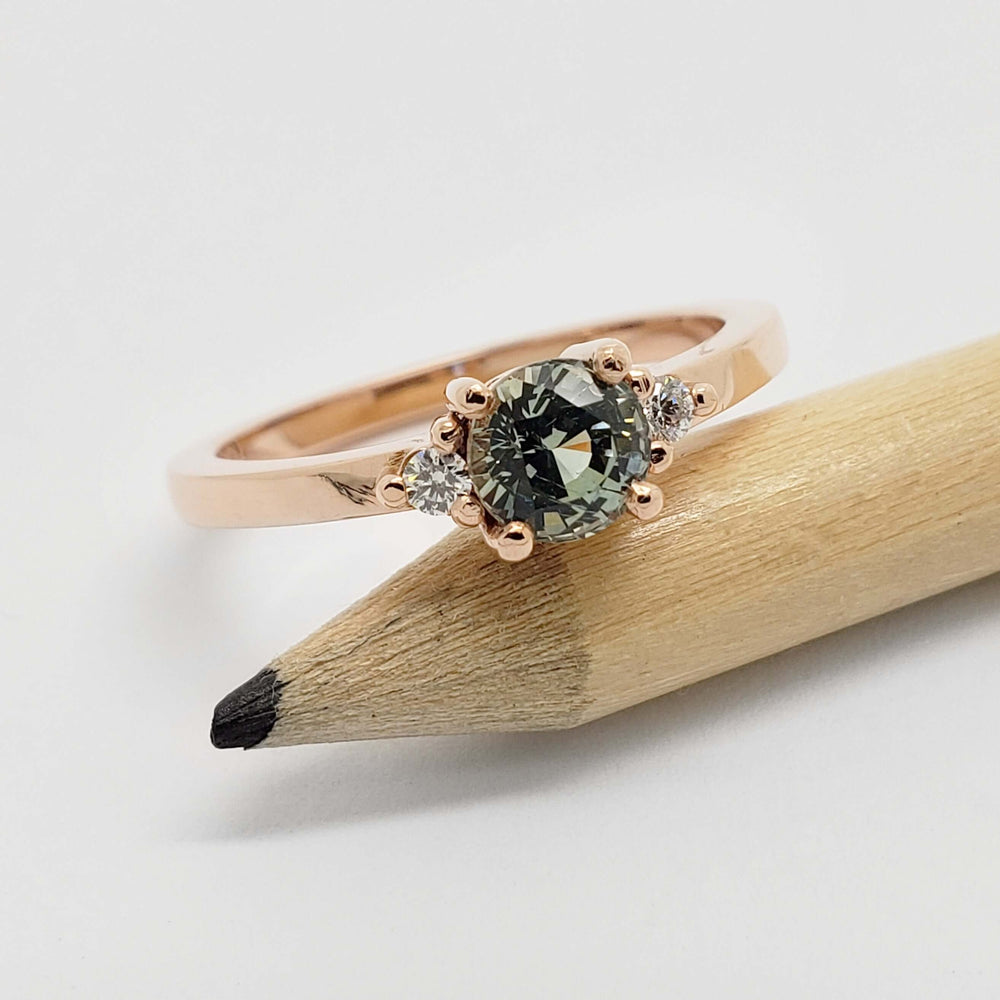 Australian sapphire and diamond rose gold ring resting on a pencil