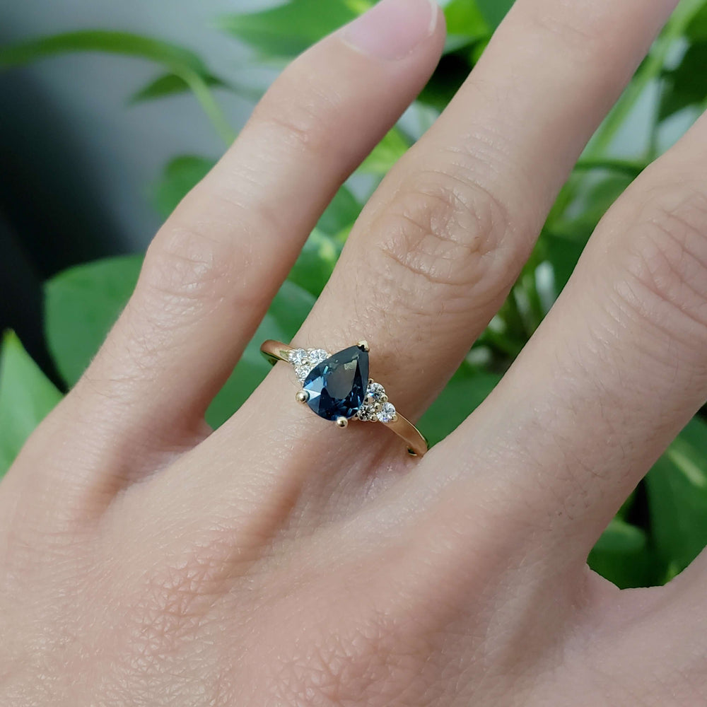 Australian sapphire and diamond yellow gold ring worn on hand, with green background
