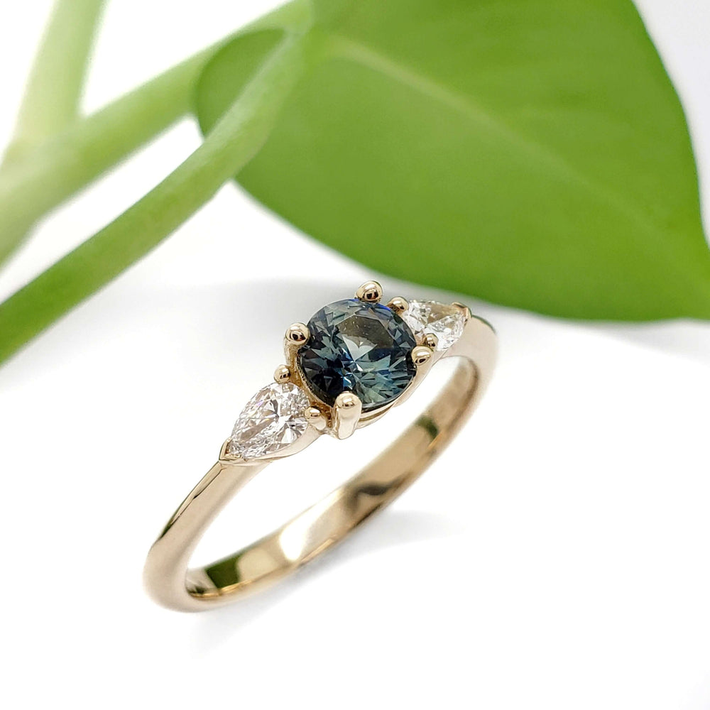 Australian sapphire and lab diamond ring in yellow gold, shown with green leaf background