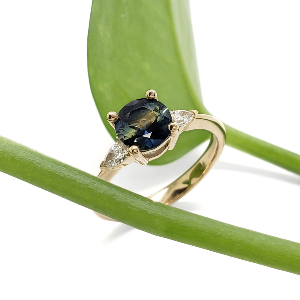 Australian sapphire and lab diamond ring in yellow gold, displayed with green leaf