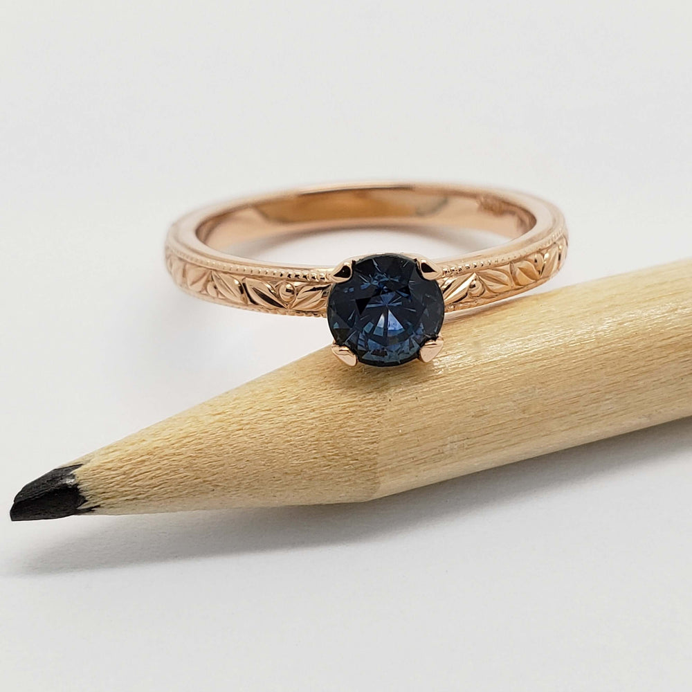 Australian sapphire engagement ring in rose gold, engraved band, displayed on a pencil