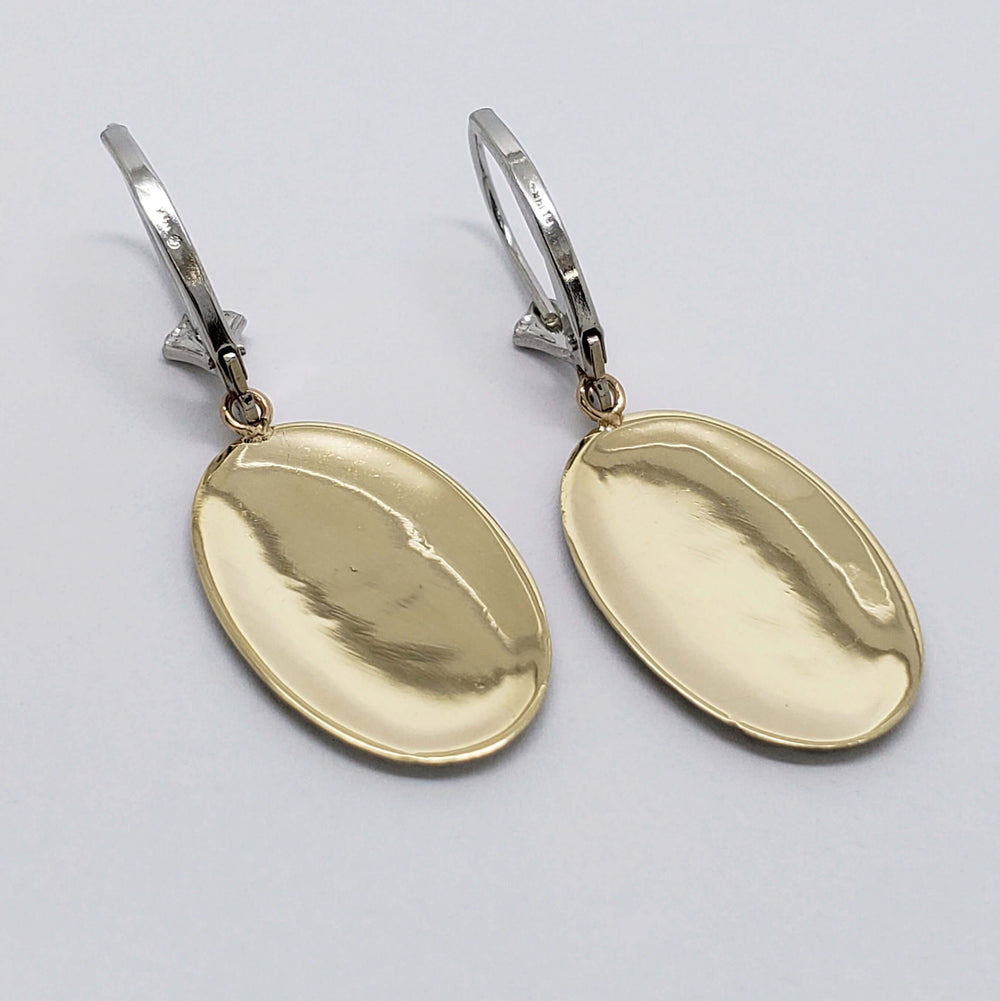 Back view of oval drop earrings showing polished yellow gold surface and white gold hooks