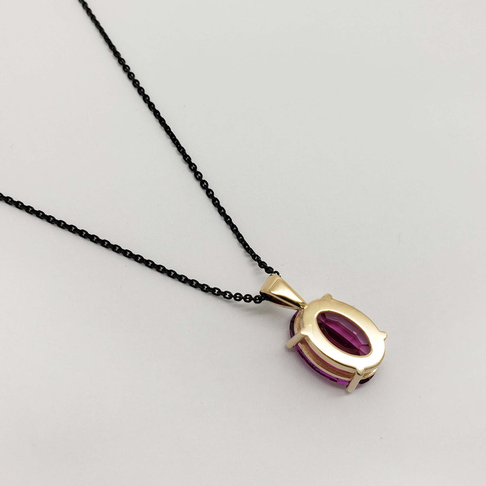 Back view of 14kt yellow gold pendant with oval pink sapphire and black chain