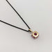 Back view of 14kt yellow gold pink spinel pendant on black chain, white background